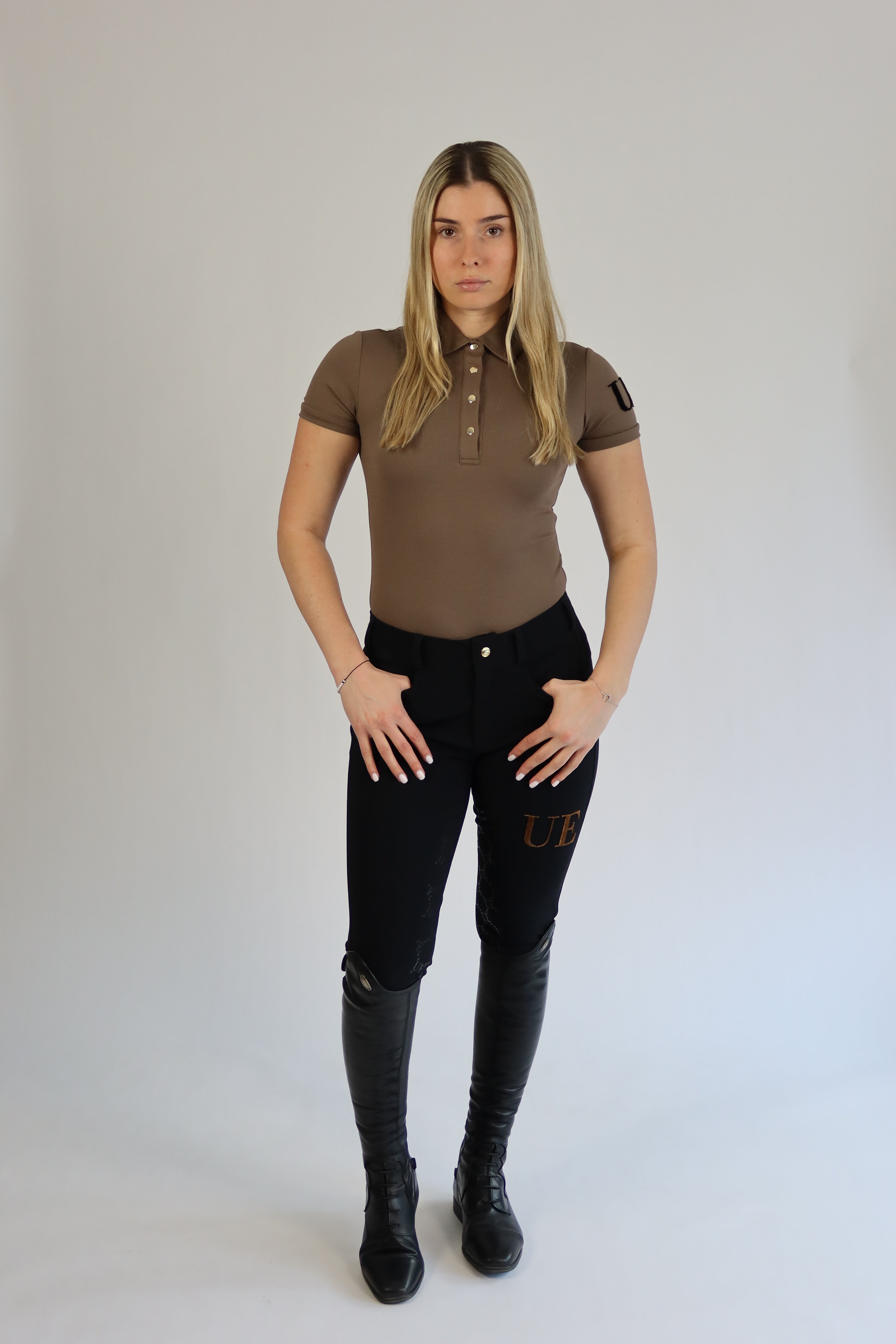 Person wearing a brown shirt and black pants on a plain background